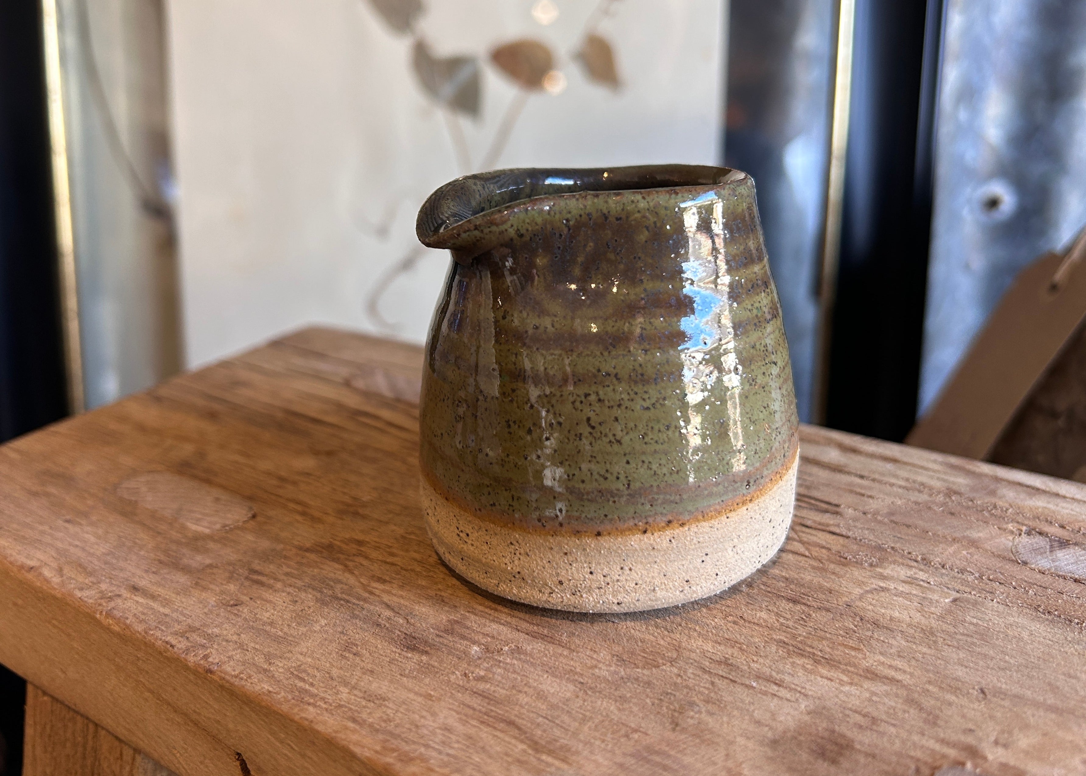 Green ceramic jar with a textured surface on a wooden surface