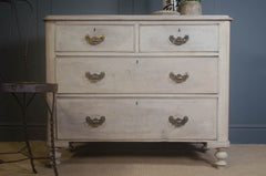 Vintage-style dresser with four drawers against a dark wall.