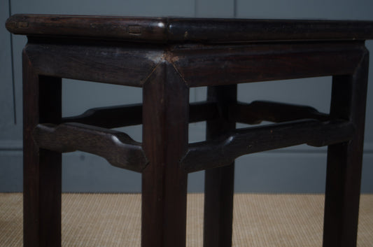 Dark wooden stool with intricate design on a plain background