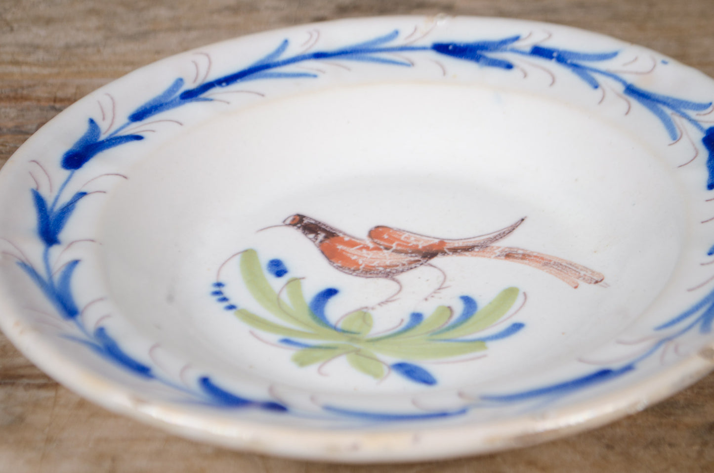 Vintage Quimper faience deep plate with hand-painted bird motif and blue decorative border on a white glazed ground.