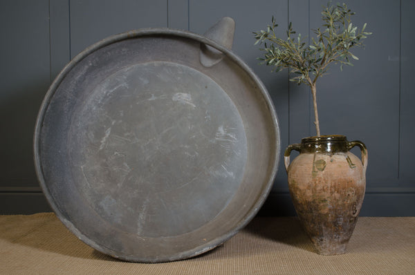 Large round metal tray with a handle next to a small vase with a plant on a textured surface. Water feature, reclaimed, bath, zinc, french, planter, herb, duck pond