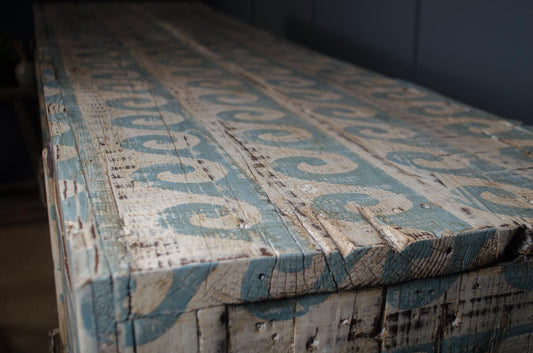 Decorative wooden box with intricate carvings and blue patterns on a dark background