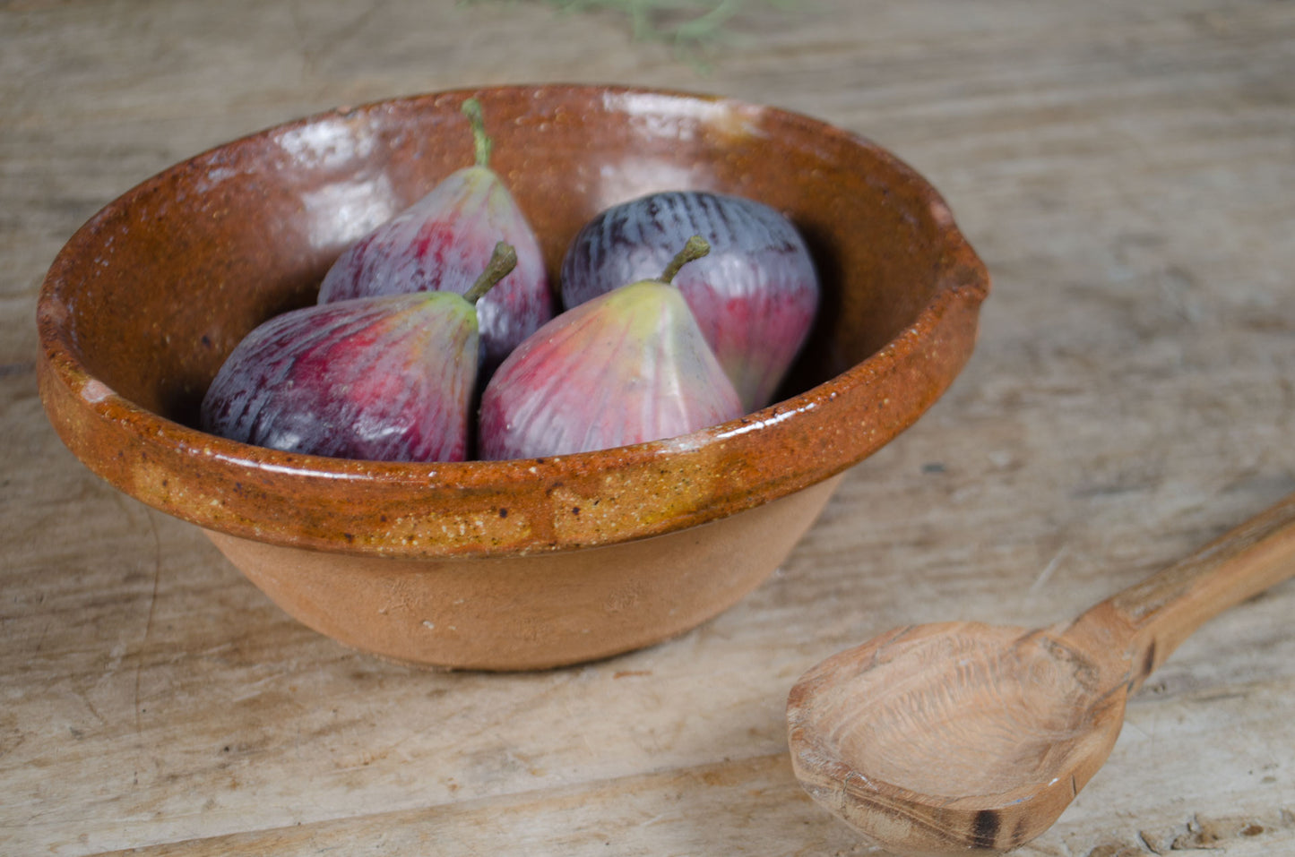 Terracotta bowl with figs on a wooden surface