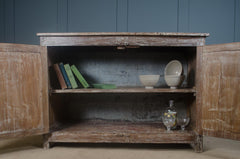 Old wooden cabinet with open doors displaying books and decorative items against a dark wall. Indian teak sideboard