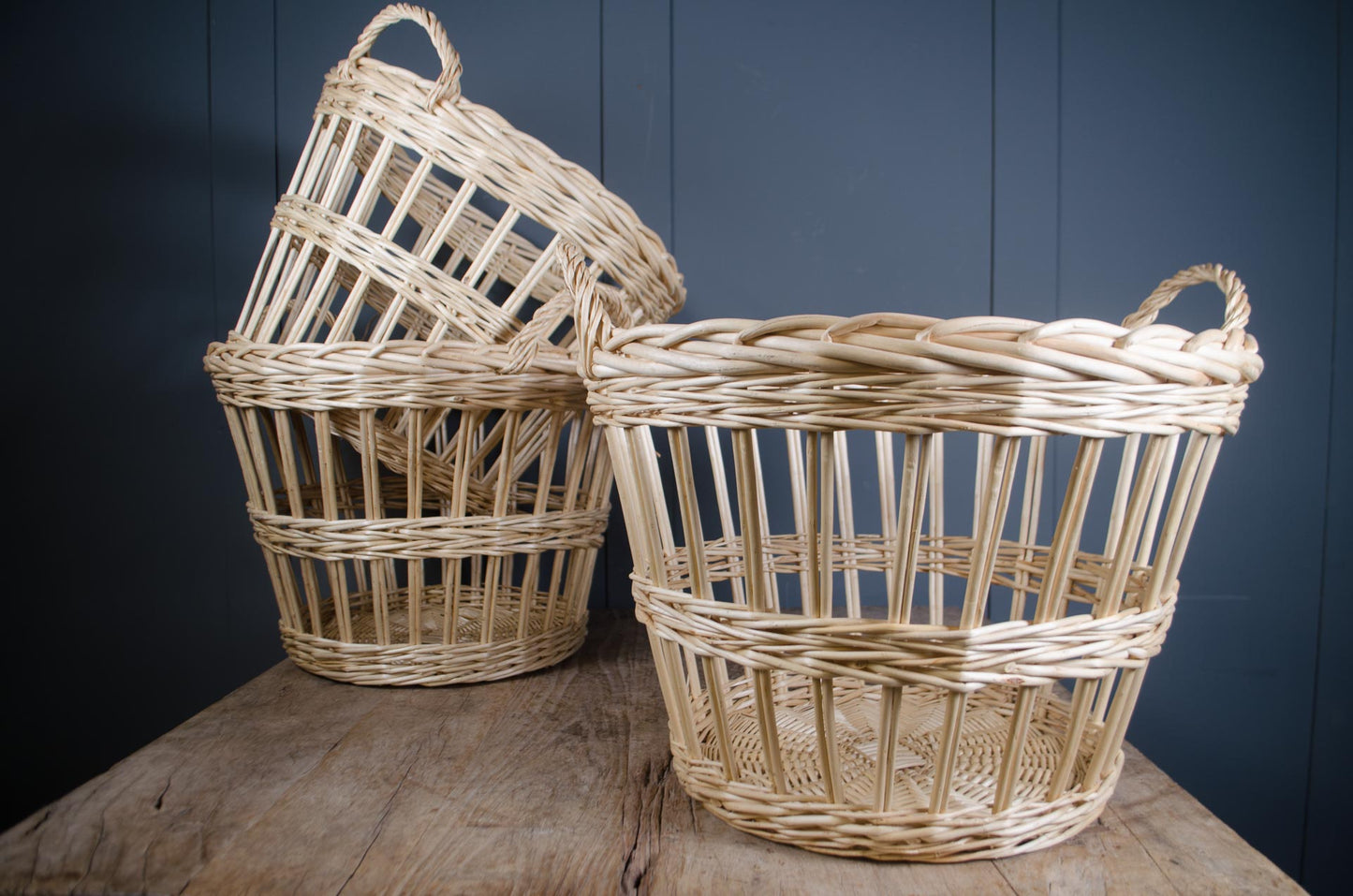 Two woven baskets on a wooden surface with a dark blue wall background