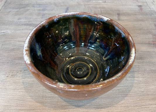 Raku Ceramic bowl with a glossy black interior on a wooden surface