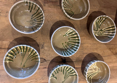 Set of mini ceramic tapas bowls with green marbled glaze, handmade Romanian stoneware on wooden table.