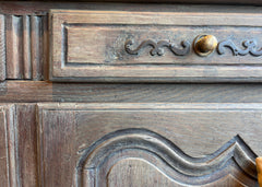 French provincial walnut sideboard with lime wash patina, removable interior shelf, and ornate brass hardware.