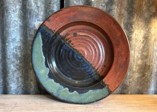 Ceramic plate with blue and red glaze on a wooden surface and metal background