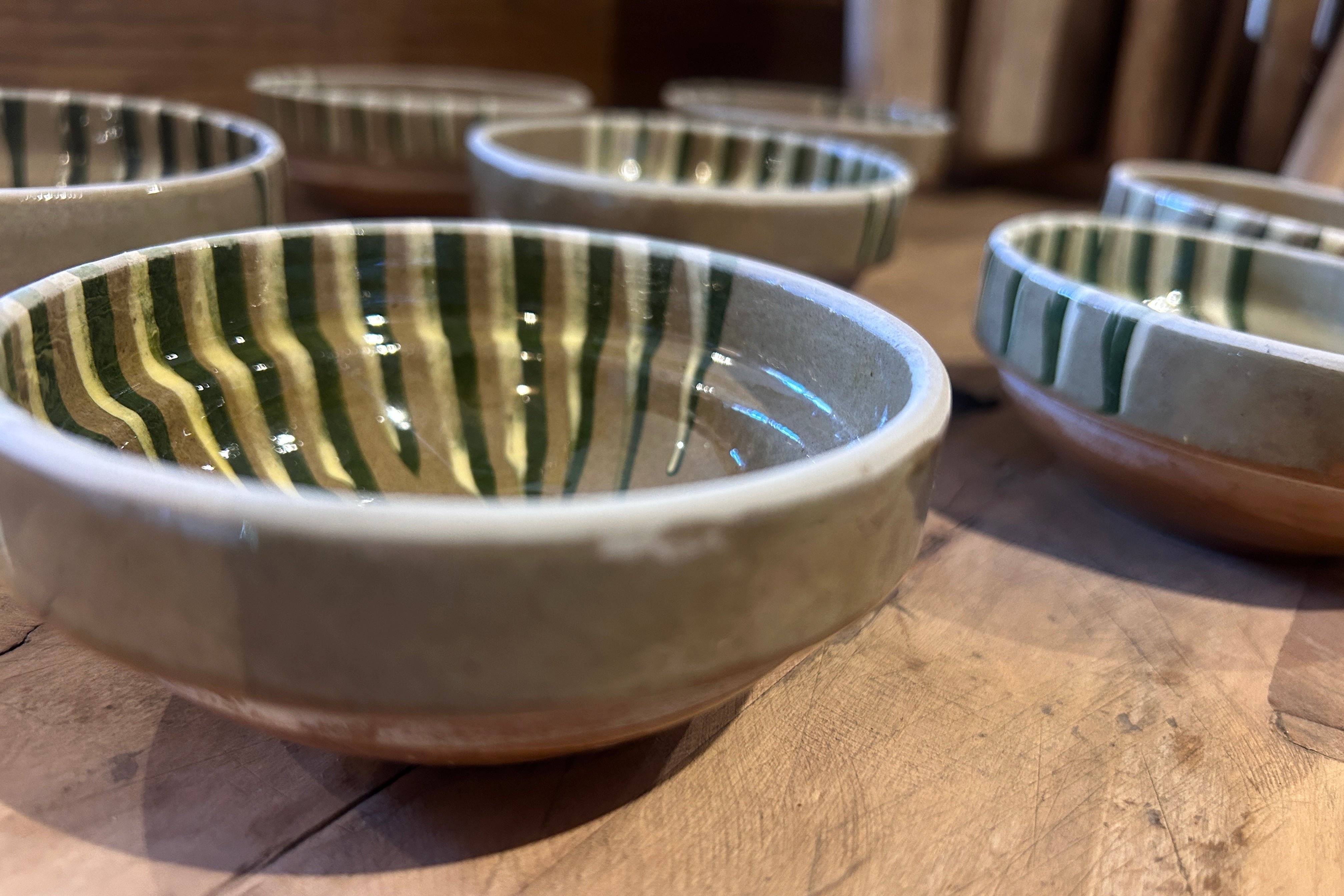 Handmade mini marble glazed bowls in green and taupe arranged on a wooden surface, Romanian pottery for tapas and nibbles.