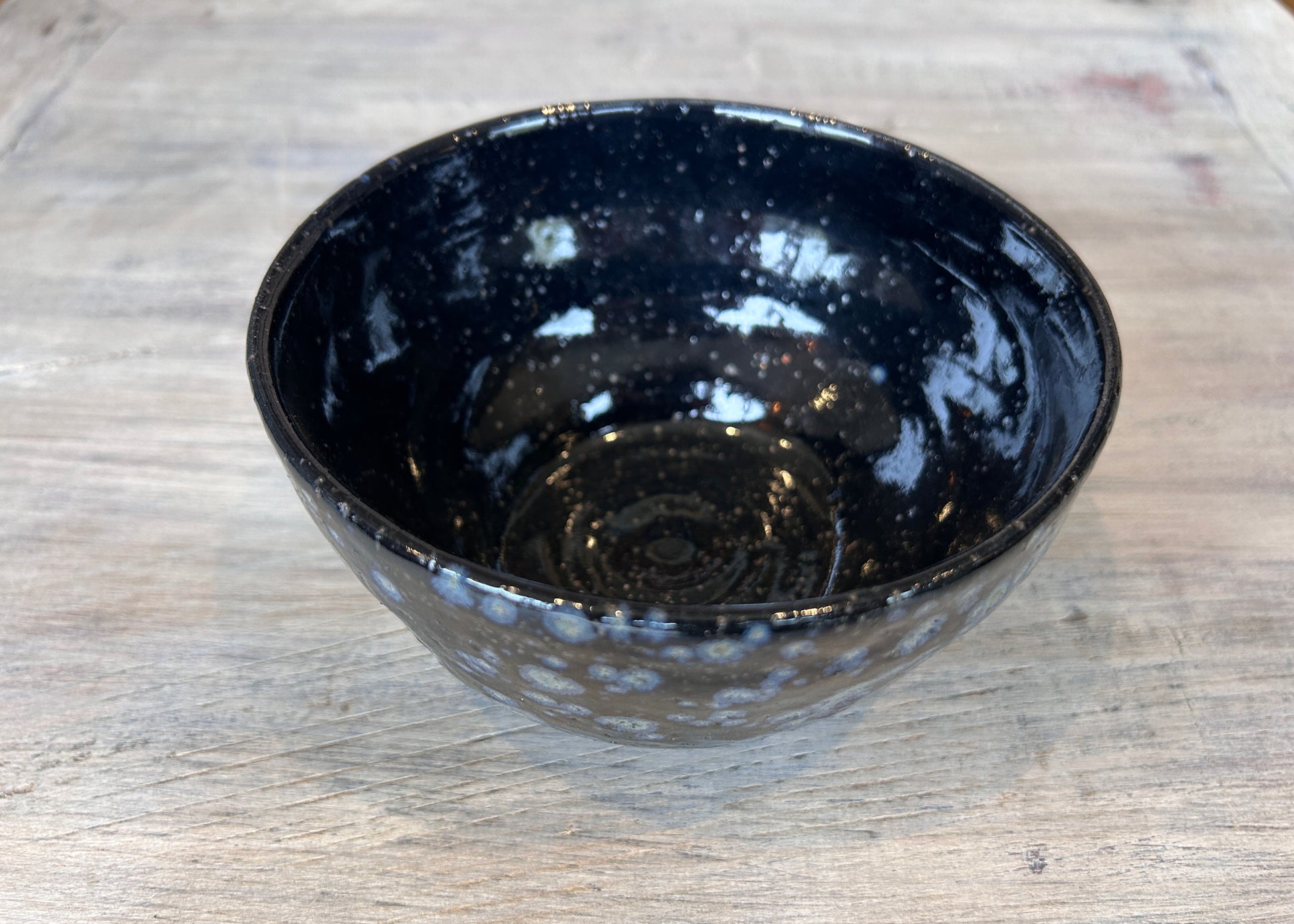 
Navy blue ceramic bowl on a wooden surface and speckled Raku glaze