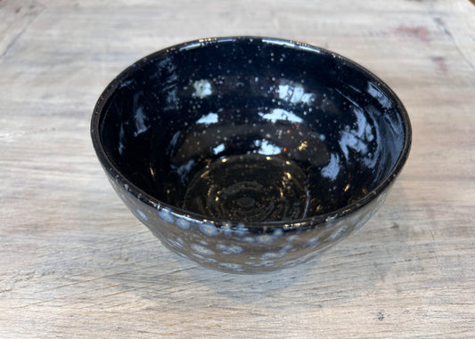 Navy blue ceramic bowl on a wooden surface and speckled Raku glaze