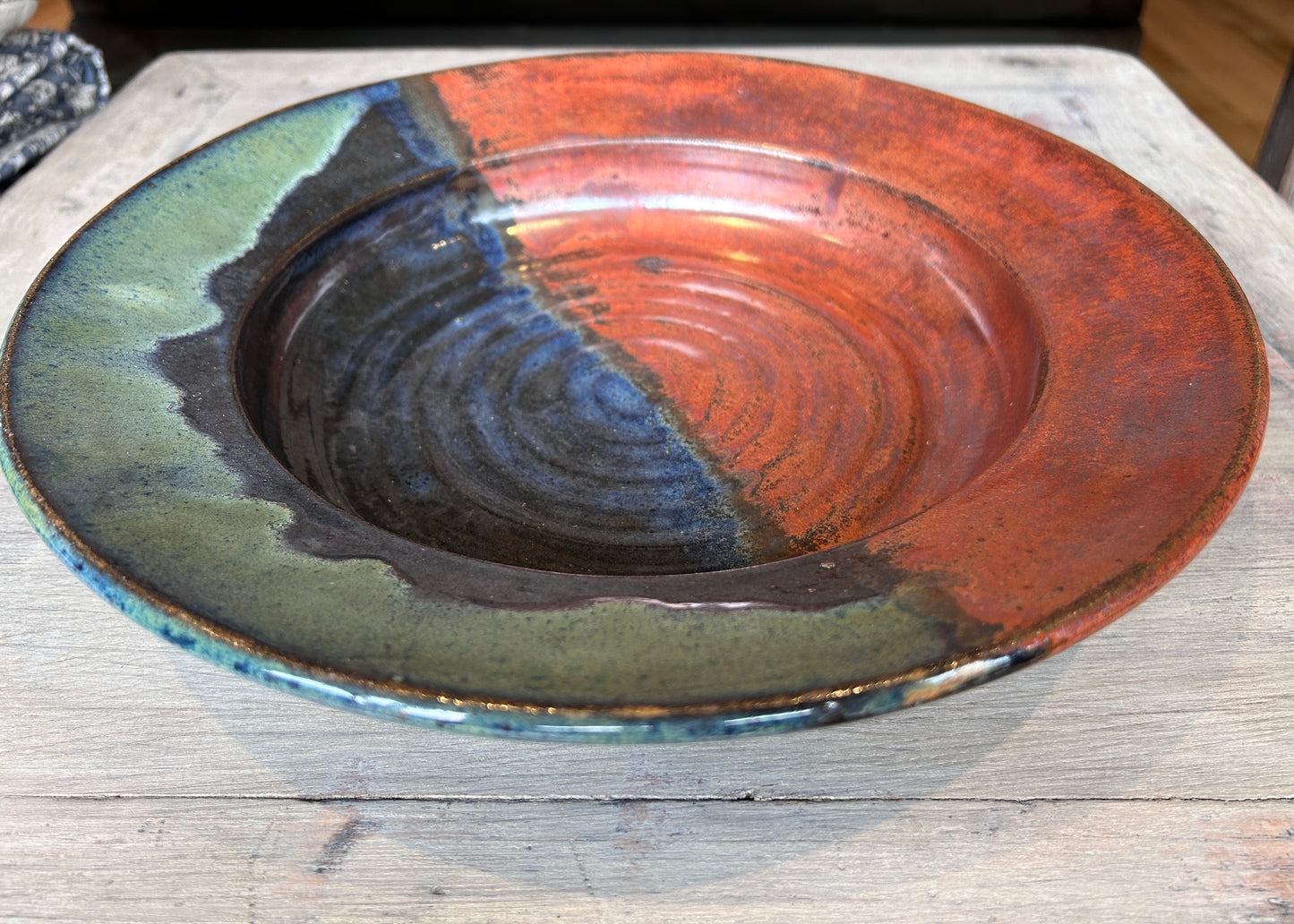 hand thrown pasta bowl Ceramic bowl with multicolored glaze on a wooden surface