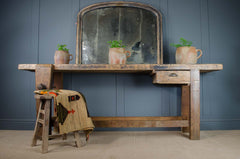 rustic kitchen island table with metal handle, reclaimed wood, foxed mirror, with french terracotta confit jars on top of antique workbench and rug tapestry draped over a stool