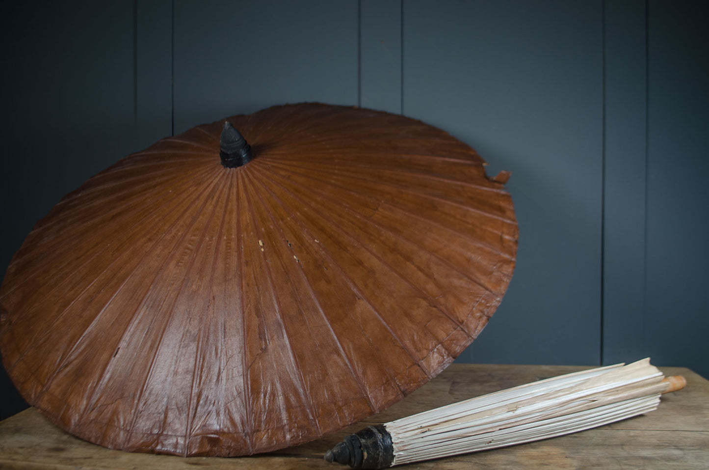 Brown umbrella on a wooden surface with a dark blue wall background