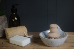 Cleaning supplies including a bottle, sponge, soap, and scrubber on a wooden surface.