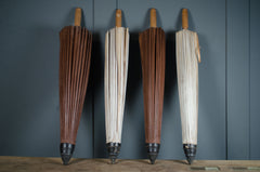 Two pairs of wooden-handled umbrellas against a dark gray wall.