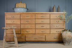 Wooden dresser with multiple drawers against a blue wall, with decorative items on top.