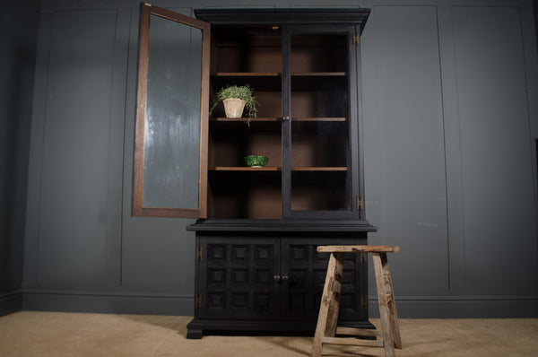 Dark wooden cabinet with open doors against a gray wall