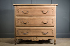 Wooden dresser with four drawers against a gray wall.