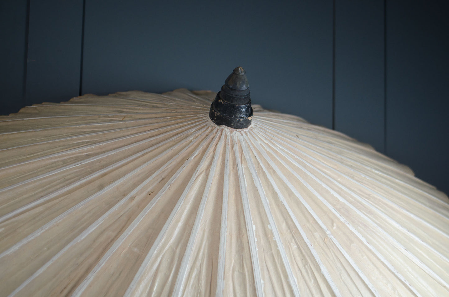 Close-up of a traditional Japanese umbrella with a dark handle against a dark background