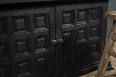 Black cabinet with panel doors and a wooden ladder in front