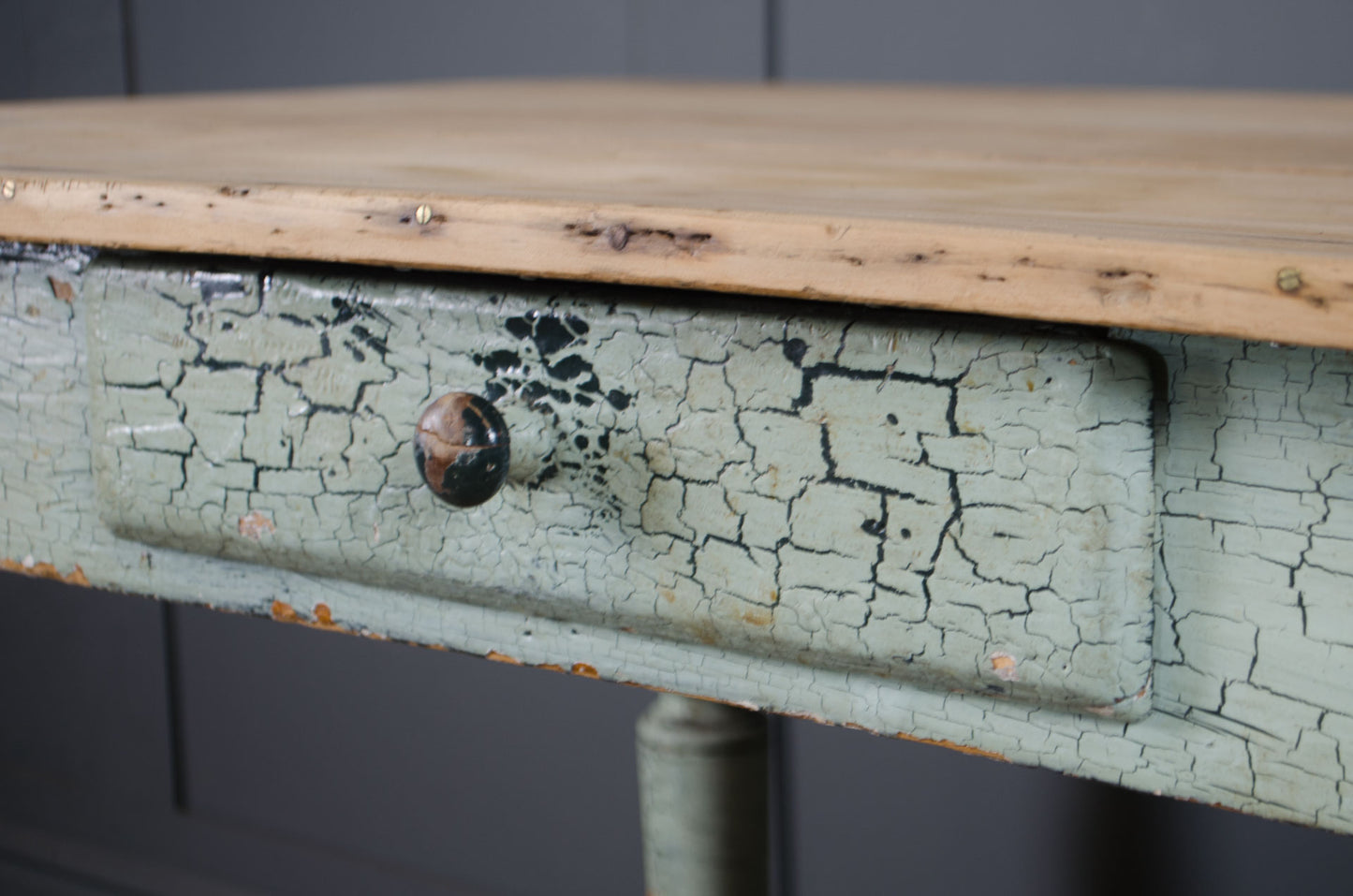 Worn wooden table with a cracked green paint finish on a dark background