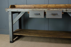 Wooden workbench with metal drawers against a gray wall.