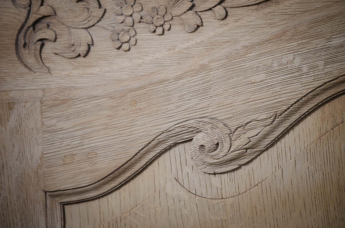 
Close-up of a light natural wood surface with carved decorative scrollwork and floral details.