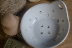 White colander with holes on a wooden surface