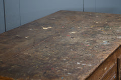 Old wooden desk with a worn surface against a blue wall.