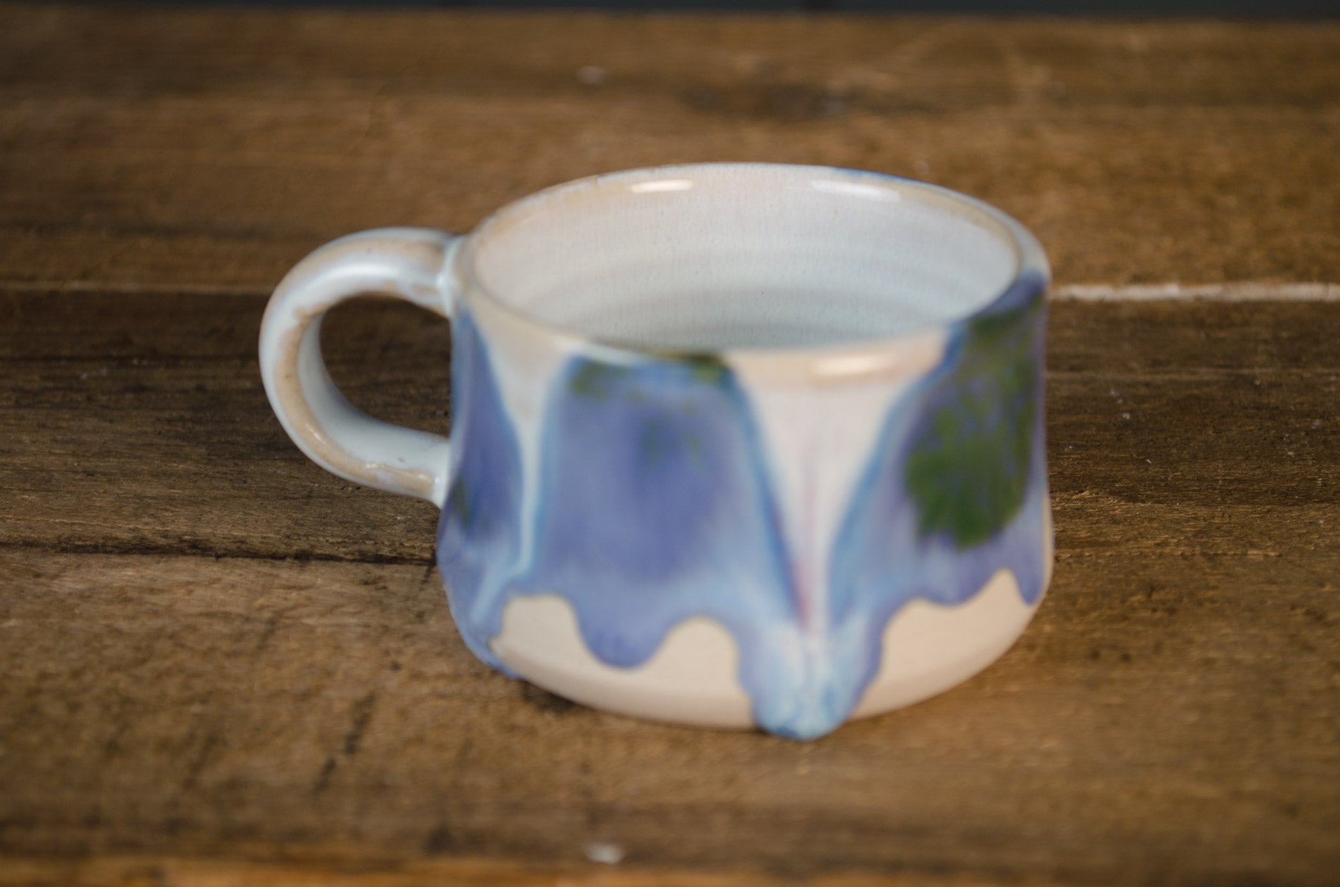 Ceramic mug with blue and green abstract design on a wooden surface