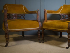 Pair of mustard velvet chairs with wooden frames against a grey wall.