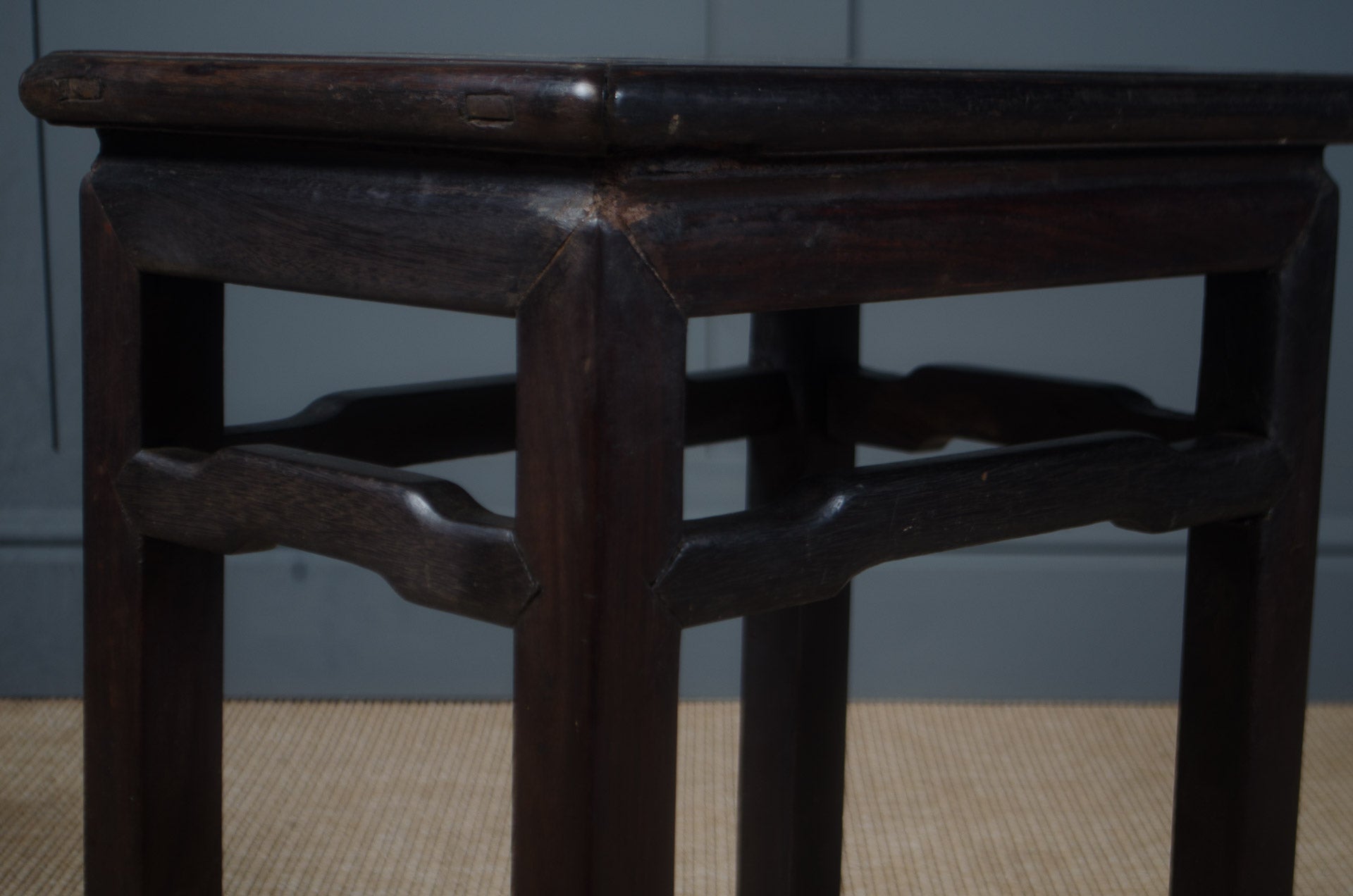 
Dark wooden stool with intricate design on a plain background