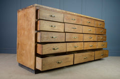 Wooden dresser with multiple drawers against a blue wall.
