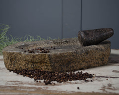 Stone mortar and pestle with peppercorns on a rustic surface