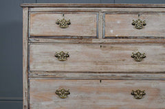 Wooden dresser with distressed finish and brass handles against a gray background