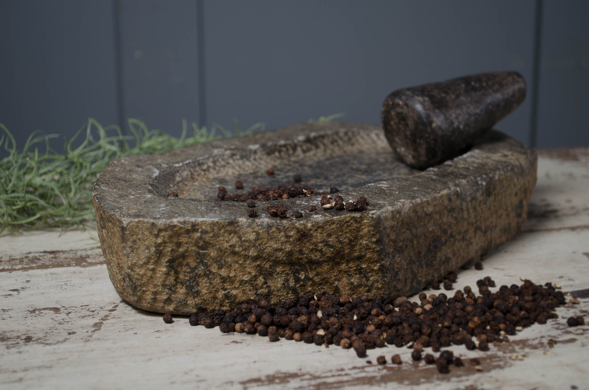 Mortar and pestle with peppercorns on a rustic wood reclaimed worktop