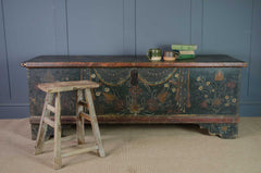 Vintage wooden chest with floral patterns on a blue wall background