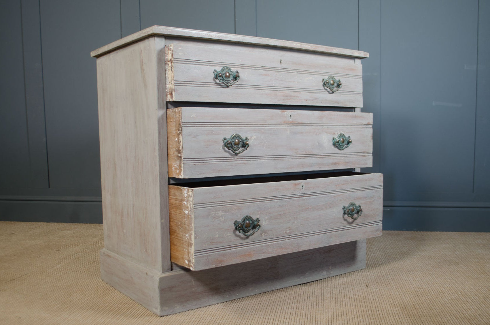
Wooden dresser with three drawers against a gray wall.