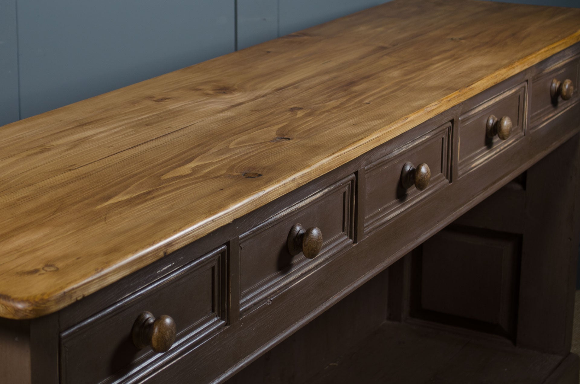Wooden dresser with a rustic finish and metal knobs against a grey wall