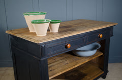 Wooden table with three ceramic pots on top against a blue wall.