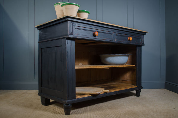Dark reclaimed wooden kitchen island cabinet with a single drawer and open shelf against a blue wall.