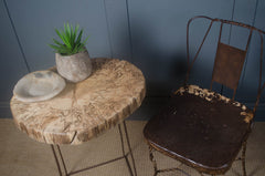 Wooden table with a plant and bowl next to an old metal chair against a blue wall.