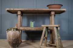 Vintage wooden table with a rustic jar and books against a blue wall.