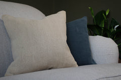 Beige and blue natural linen hempcushions on a grey sofa with a plant in the background