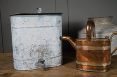 Vintage-style metal container and copper watering can on a wooden surface with a dark background