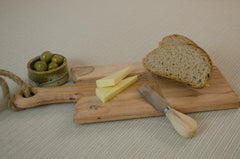 Rustic mango wood cheese board with olives, butter and sourdough bread
