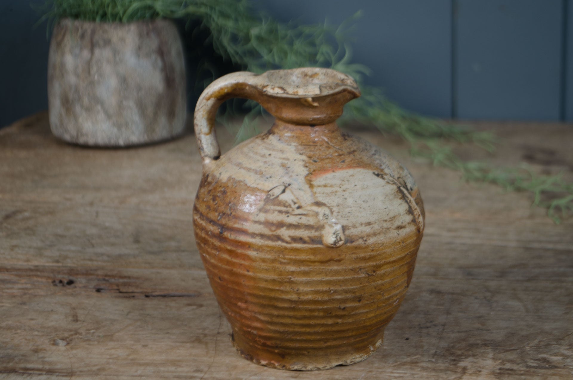 Stoneware jar with a textured surface on a wooden surface with a blurred background