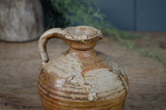 Stoneware jar with a handle on a wooden surface